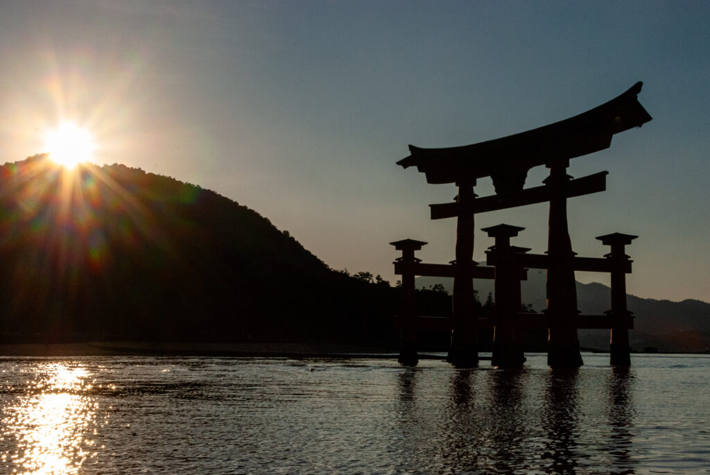 Miyajima torii gate at sunset with mountains in the background